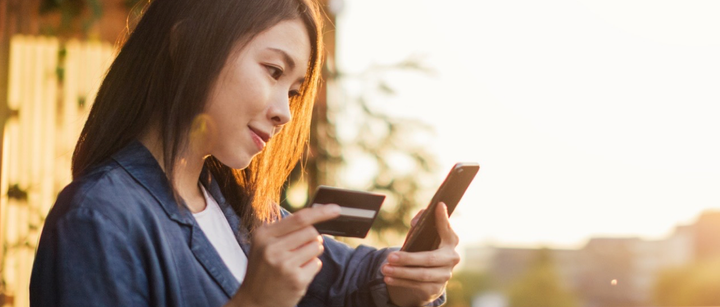 A woman holding her card to enter payment details in her mobile phone